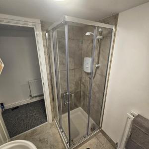 a shower with a glass door in a bathroom at Snug on Eden Derry in Londonderry County Borough