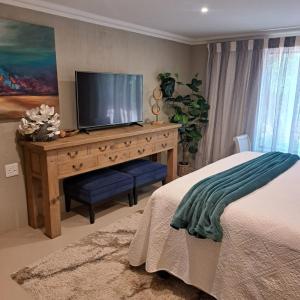 a bedroom with a dresser with a television on it at Kruger Tree Lodge in Marloth Park