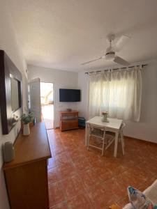 a living room with a table and a television at Duplex Barbados Aguamarga in Agua Amarga