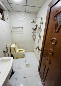 a bathroom with a toilet and a sink and a door at اليرموك 4 شوارع in Baghdād