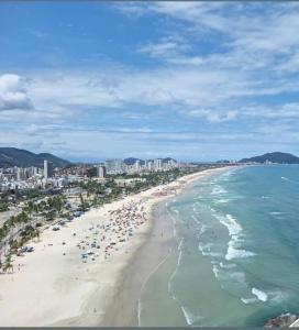 a beach with a bunch of people and the ocean at Recanto da Enseada in Guarujá