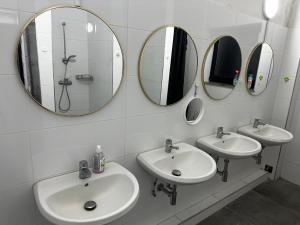 ein Badezimmer mit drei Waschbecken und Spiegeln an der Wand in der Unterkunft Dottore Privatel in Hamburg