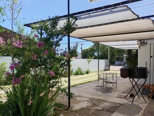 a patio with an umbrella and a table and flowers at Refugio Amaicha in Embalse +15 photos
