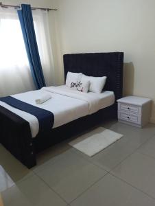 a bed with a black headboard and white pillows at Chesum's suites in Eldoret