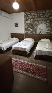 a room with two beds and a stone wall at Veranda Guest House in Berat