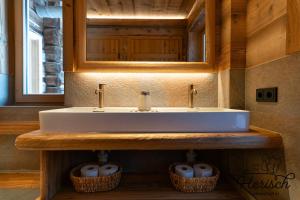 a bathroom with a sink and a mirror and two baskets at Selbstversorgerhaus Herisch in Schladming +60 photos