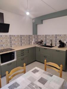 a kitchen with green cabinets and a table and chairs at Le Lorry 8 appartement in Laruns +9 photos