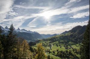 a valley in the mountains with the sun in the sky at Ganzes Haus am Bodensee in den Bergen im Appenzell in Heiden