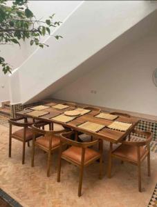 a wooden table with chairs and a table with books on it at Riad du Bab atlas in Marrakesh