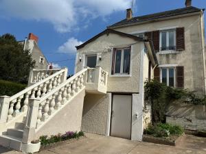 a white house with a staircase and a door at La Sinaise in Châteaumeillant