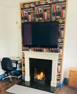 a living room with a fireplace with a flat screen tv at 2 Bedroom Workers Apartment in Barrysbrook