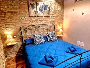 a blue bed in a room with a stone wall at Il Girasole -with Garden- in Buonconvento