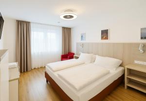 a bedroom with a white bed and a red chair at Villa Viktoria 3 - Apartments in Ingolstadt