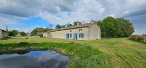 an old building in a field next to a pond at Gîtes de la Bernière in Brûlain