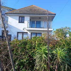 a white house behind some trees and bushes at Harbour Views, Coverack in Helston +17 photos