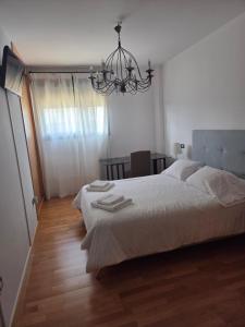 a bedroom with a bed with white sheets and a chandelier at LUCIA S HOUSE in Mairena del Aljarafe