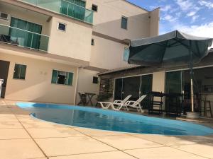 a swimming pool in front of a building with an umbrella at Pousada Souza & Souza in Barra Velha