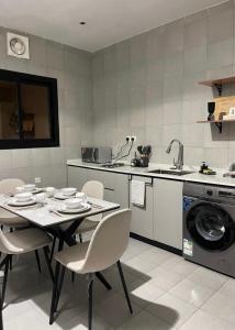a kitchen with a table and chairs and a washing machine at Riwaq suite in Jeddah