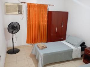 a bedroom with a bed with an orange curtain and a fan at Los Pinos de Horizonte in Fernández