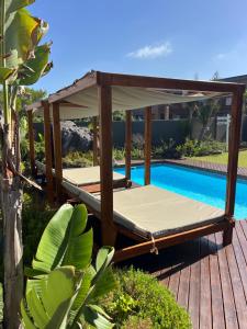 a swing bed on a deck next to a swimming pool at Oppi See Beach House in Wilderness