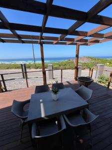 a table and chairs on a deck with the beach at Oppi See Beach House in Wilderness