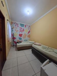 a room with two beds in it with a mural at Hotel Padre Vitor in Aparecida