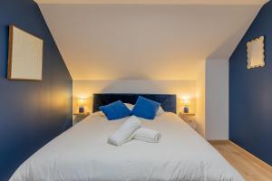 a bedroom with a large white bed with blue pillows at La Perle Bleue in Algrange