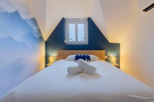 a bedroom with a large white bed with two pillows at La Perle Bleue in Algrange