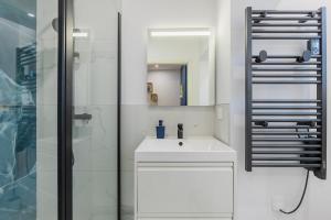 a white bathroom with a sink and a shower at La Perle Bleue in Algrange