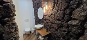 a bathroom with a sink and a stone wall at La Cueva de Villa Gardel in Icod de los Vinos +7 photos