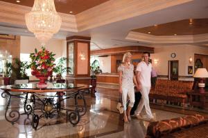 a man and a woman walking through a lobby at Occidental Marco Polo in Hammamet