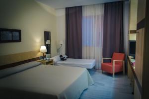 una habitación de hotel con 2 camas y una silla roja en Hospedería Mirador de Llerena, en Llerena
