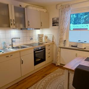 a kitchen with white cabinets and a sink and a table at Haus Eickert - Ferienwohnung in Undeloh