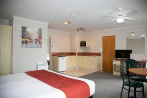 a hotel room with a bed and a table and a kitchen at Bella Vista Motel Hamilton in Hamilton