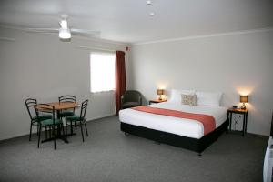 a hotel room with a bed and a table and chairs at Bella Vista Motel Hamilton in Hamilton