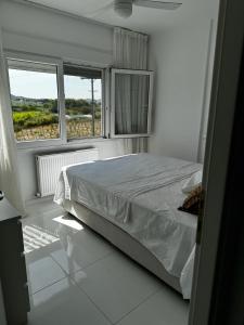 a white bedroom with a bed and two windows at Enlightened Escape in Nea Peramos