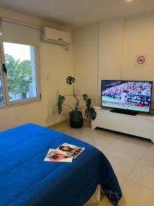 a bedroom with a blue bed and a flat screen tv at La Suitte in Bahía Blanca