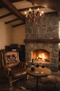 a fireplace with a chair and two glasses of wine at Mobbiton Mostar - Magical Underground Retreat in Mostar
