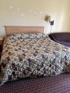 a bed in a hotel room with a quilt on it at All Star Inn in Bunkie