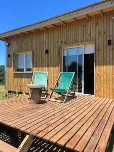 a deck with two chairs and a table and a building at Casa Lobos en Chapadmalal in La Estafeta