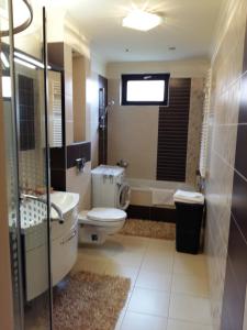 a bathroom with a toilet and a tub and a sink at City Centre Apartment in Győr