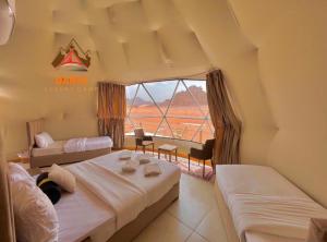 a bedroom with two beds and a large window at Daria Luxury Camp in Wadi Rum