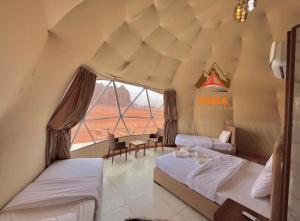a bedroom with two beds and a large window at Daria Luxury Camp in Wadi Rum +114 photos