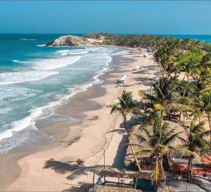 a beach with palm trees and the ocean at El Refugio II, cerca Playa El Agua y Playa Parguito, VENEZUELA in Loma de Guerra