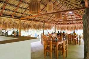 a restaurant with tables and chairs and a straw roof at Hotel Coral Sand Islas Del Rosario in Isla Grande