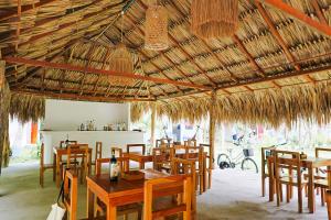 a restaurant with tables and chairs and a straw roof at Hotel Coral Sand Islas Del Rosario in Isla Grande +31 photos