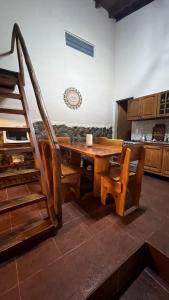 a dining room with a wooden table and a staircase at casa rustica dos dormitorios con pileta in Huerta Grande