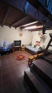 a living room with a couch and a television at casa rustica dos dormitorios con pileta in Huerta Grande