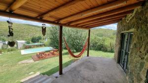 a patio with a hammock outside of a house at casa rustica dos dormitorios con pileta in Huerta Grande