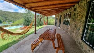 a porch with a bench and a hammock on a house at casa rustica dos dormitorios con pileta in Huerta Grande